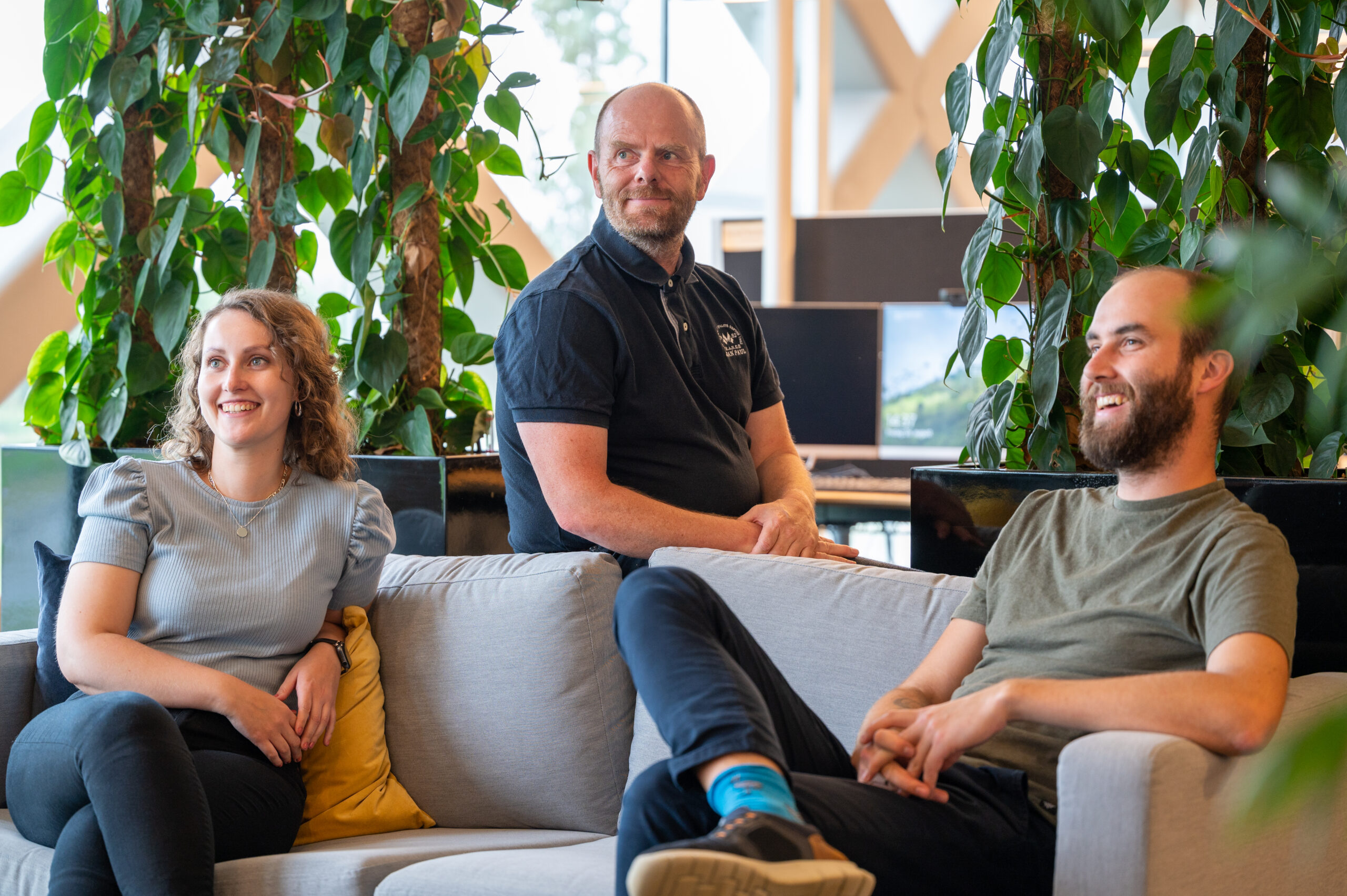 Tre glade IT-konsulenter sitter i sofaen. Foto.